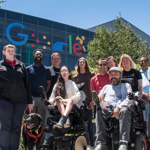 Members of Google’s Disability Alliance in front of a campus building featuring Google’s disability logo